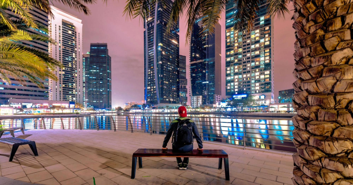 a man sitting on a bench viewing Dubai Towers
