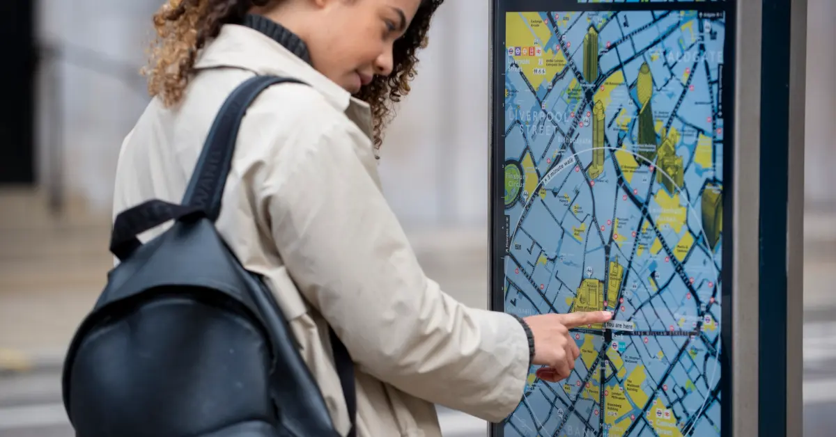 Women checking bus routes to Al Ras metro on a street screen