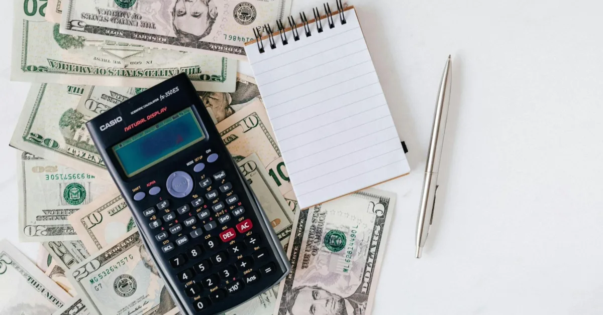 A picture showing cash, calculator and a notebook to calculate the cost of living in Fujairah