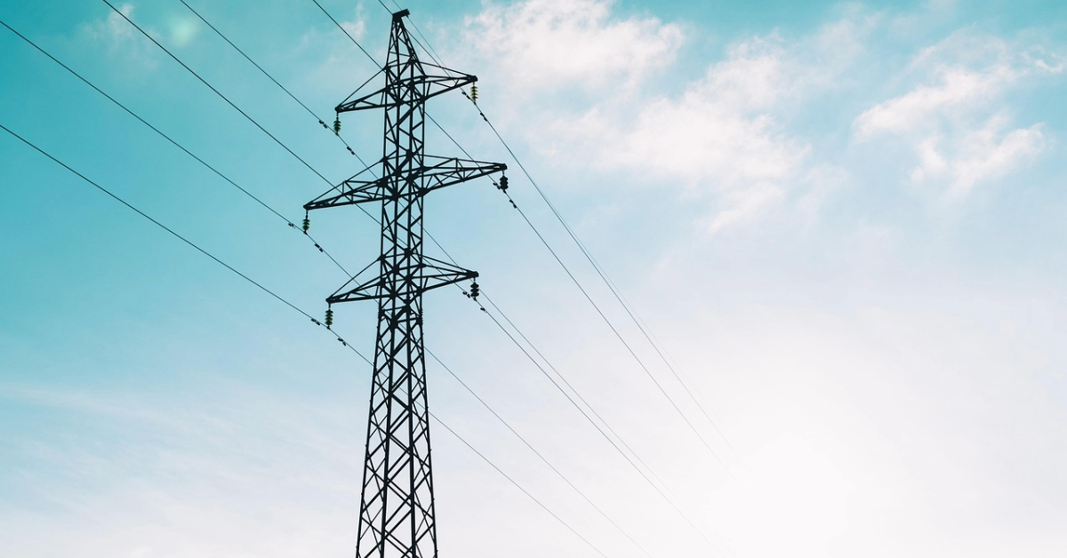 High voltage electricity pylon silhouetted against a clear blue sky