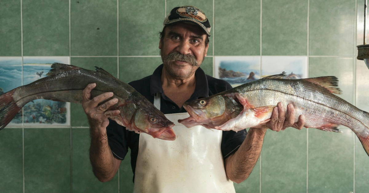 fisherman holding two fish in RAK fish market
