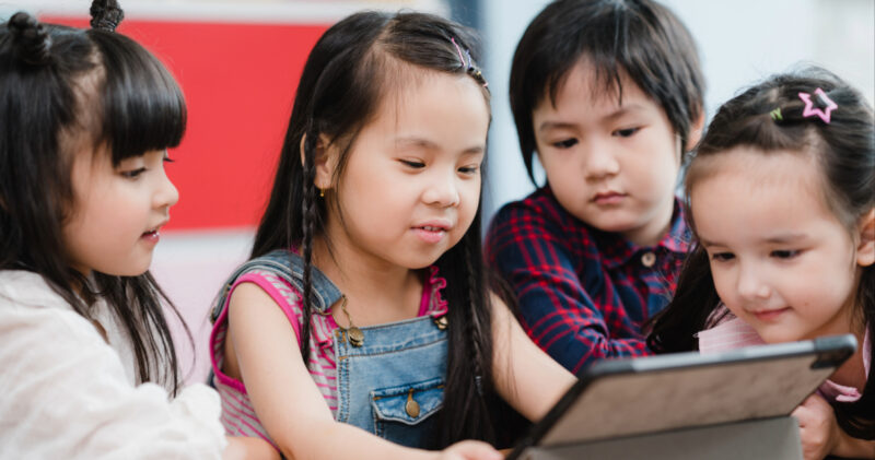 group of children using a tablet to learn in a classroom