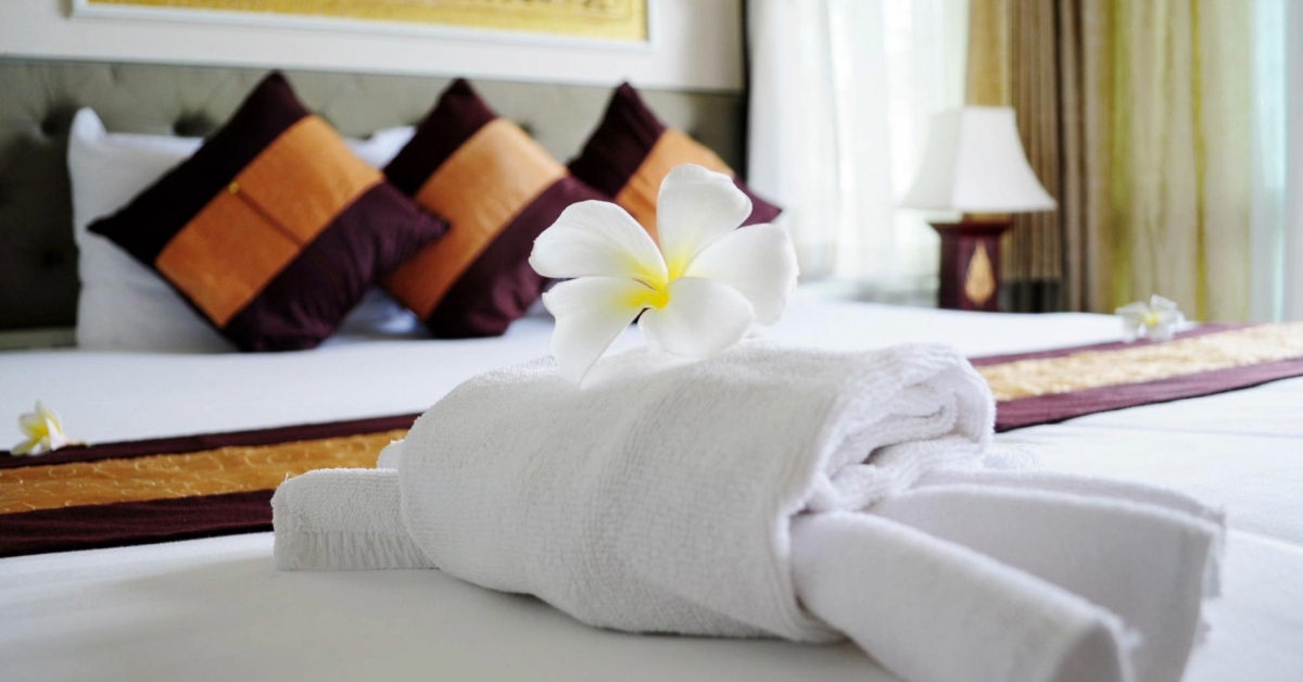 White towel with a frangipani flower on a white bed in a luxury boutique hotel bedroom