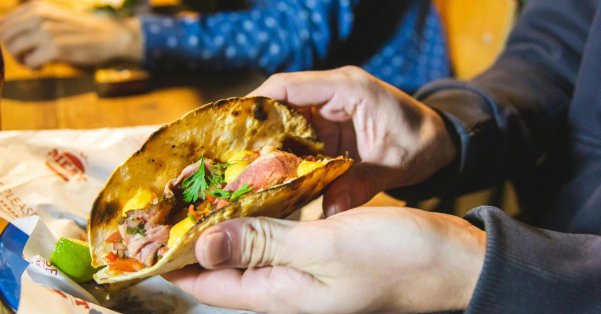person holding a taco in a restaurant