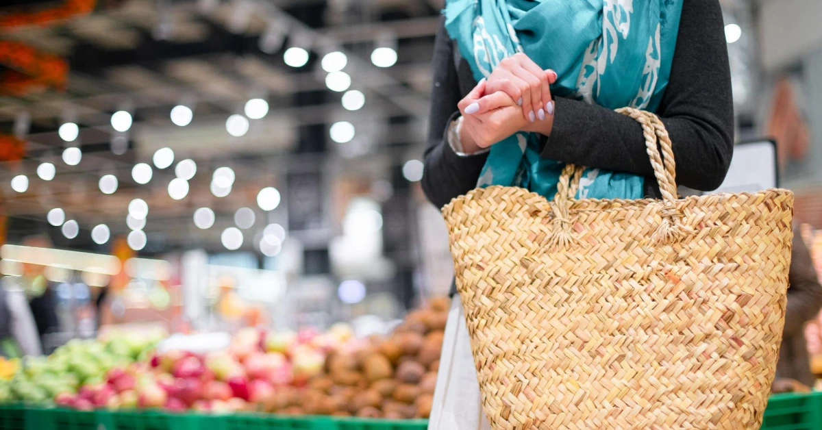 صورة امرأة تحمل حقيبة تسوق بأحد الأسواق