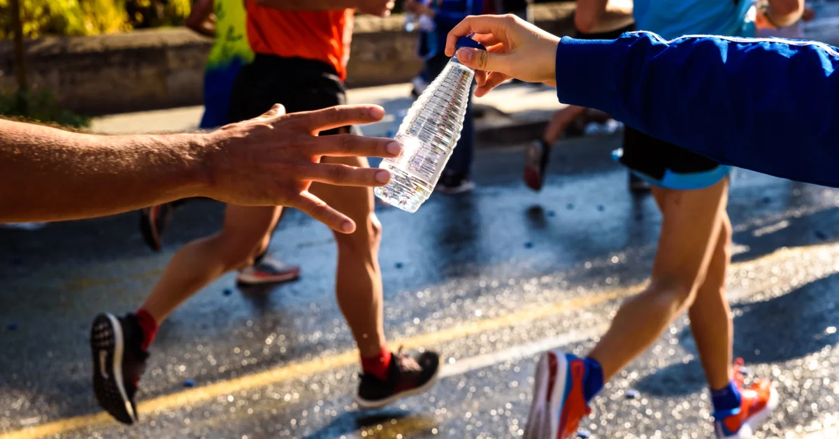 Runner collects a bottle of water to hydrate during a marathon