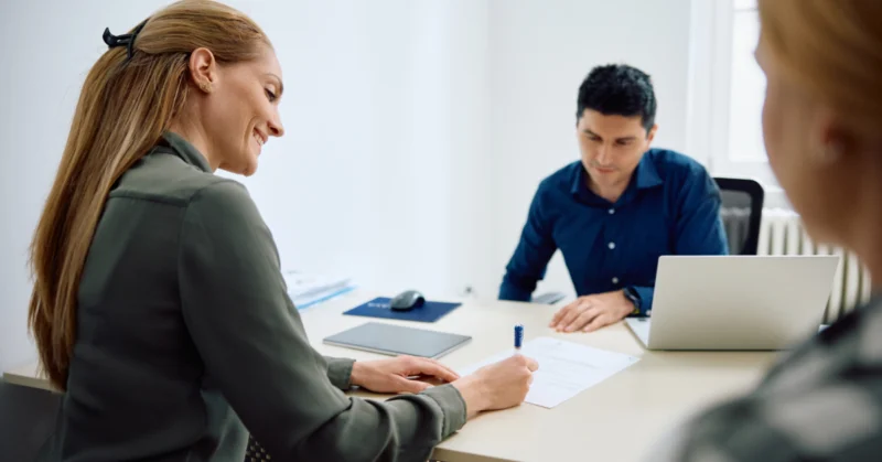 Mother signing documents for her daughter's school enrollment at the principal's office