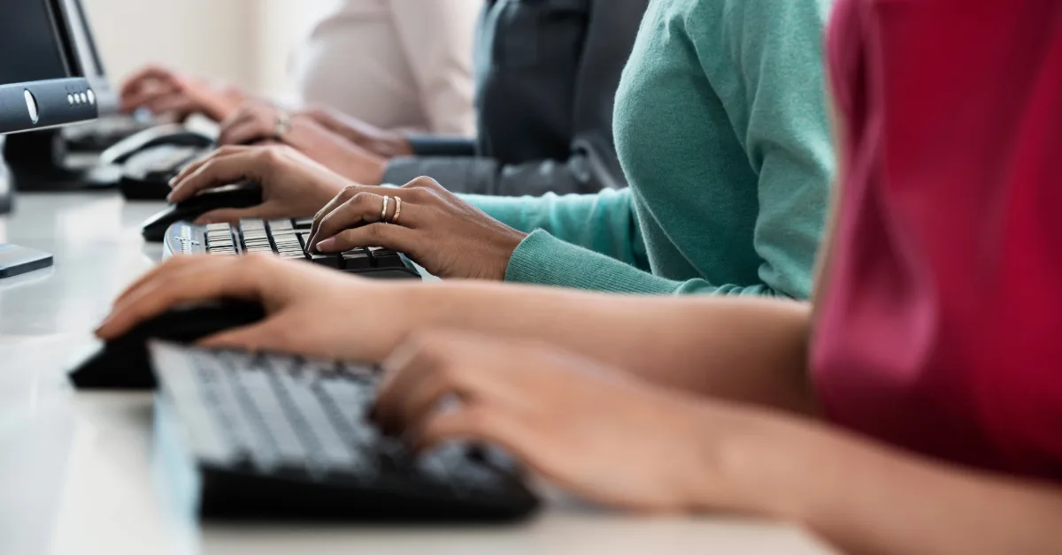 People typing on computer keyboards at a service or customer support desk.
