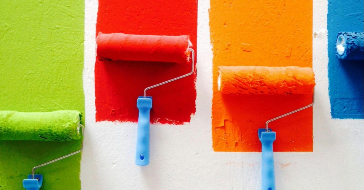 Four colours displayed as paint swatches being applied to a wall with a paint roller.