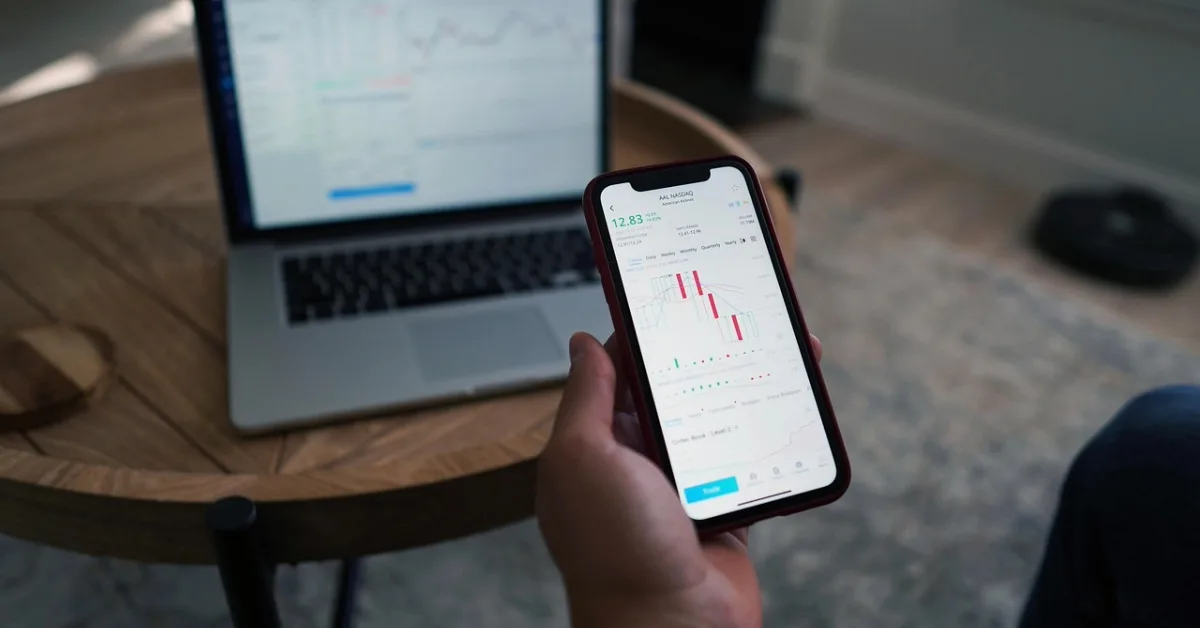 Someone holding a phone calculating stocks