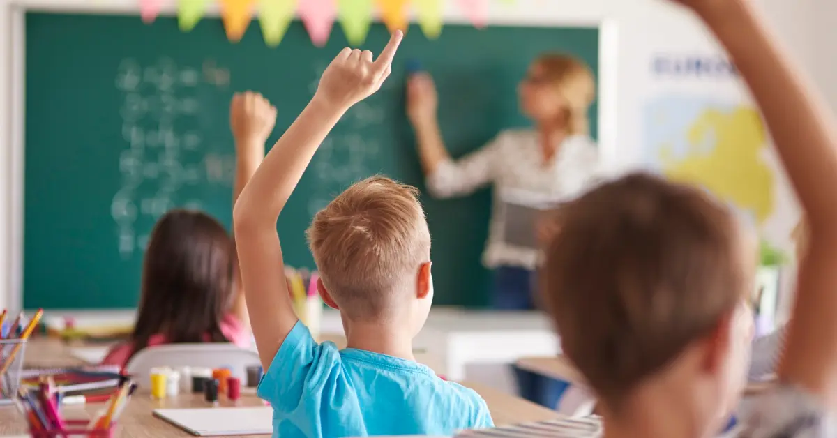 Students raising hands in class to answer