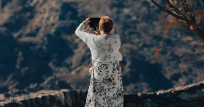 Woman photographing a scenic mountain landscape with a camera, capturing the beauty of nature