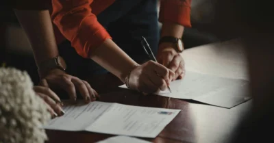 A couple signing documents at a bank