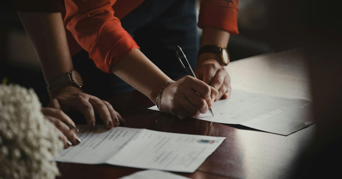 A couple signing documents at a bank