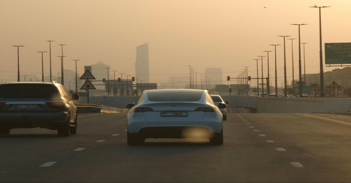 A Tesla gliding through Dubai’s roads under a golden sunset