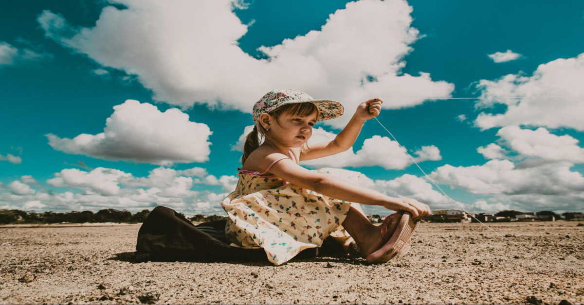 Child sitting on a sandy beach on a sunny day