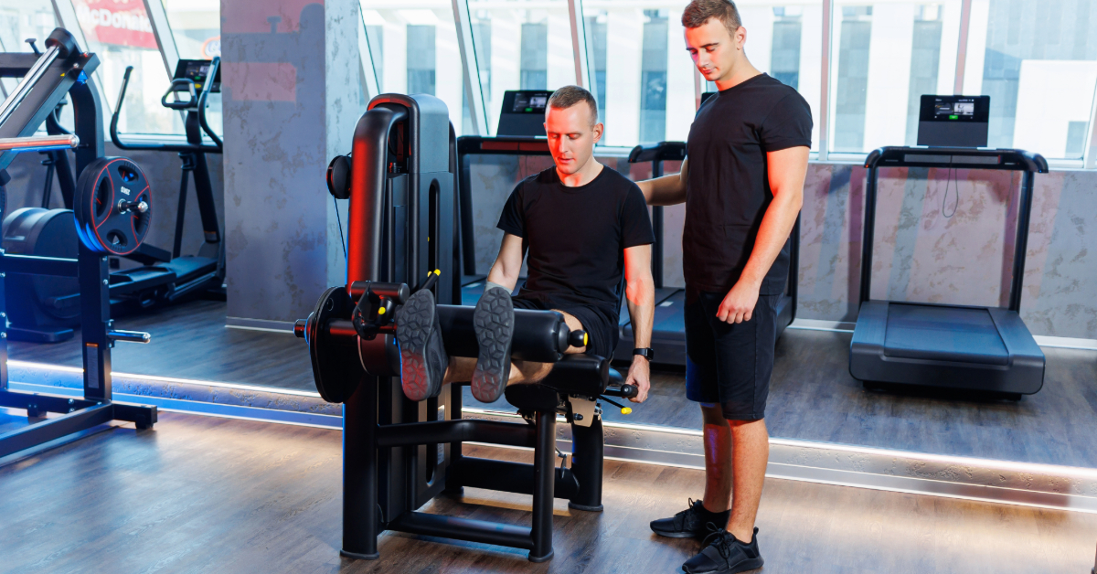 A man with a trainer in the fitness room