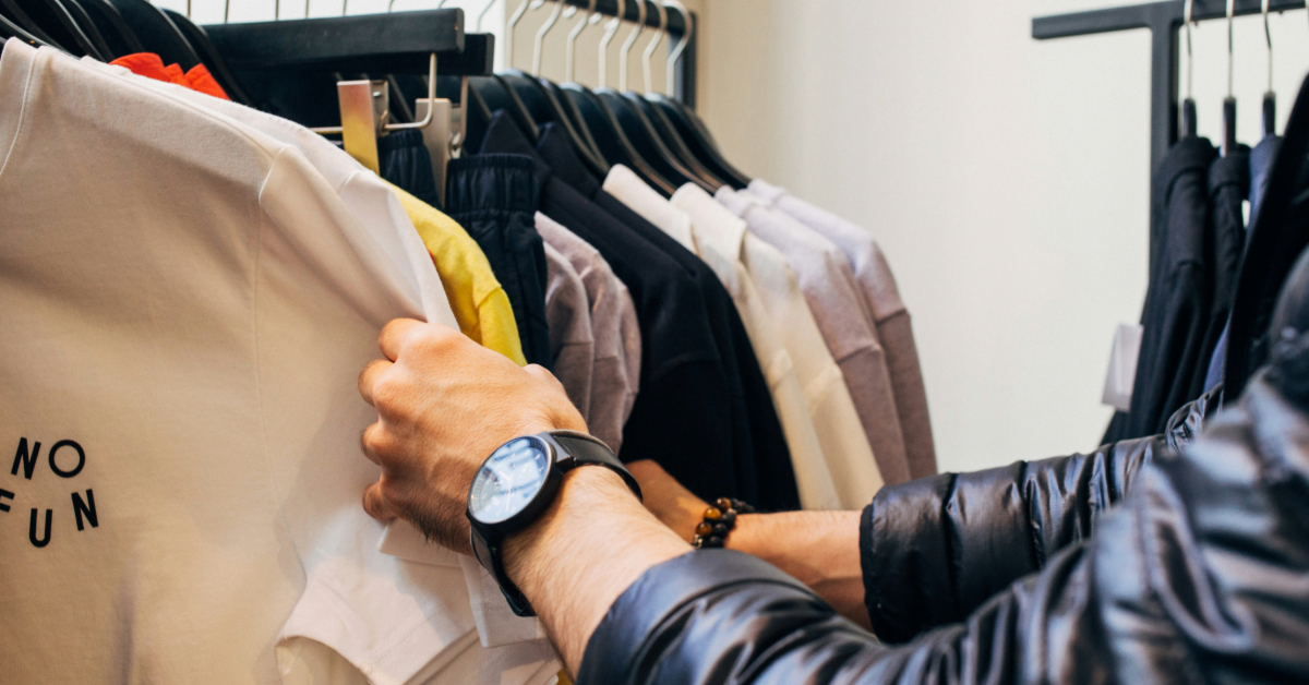A man browsing through various shirt options in a store