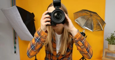 A girl holding her camera in front of her face, as if taking a photo