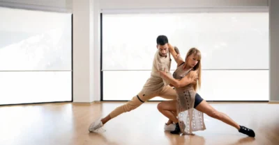 A male and female instructor demonstrating a Bachata pose
