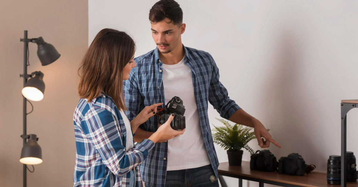 A man demonstrating different camera lenses to a woman