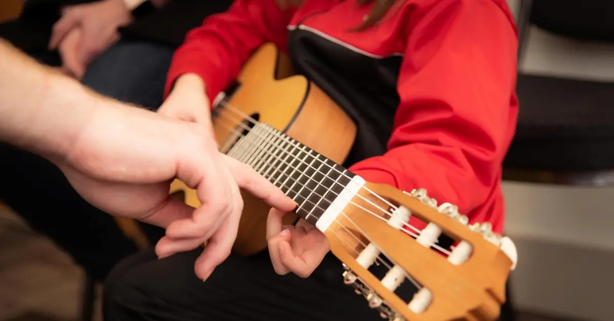 A teacher instructing a student in a guitar class in Dubai