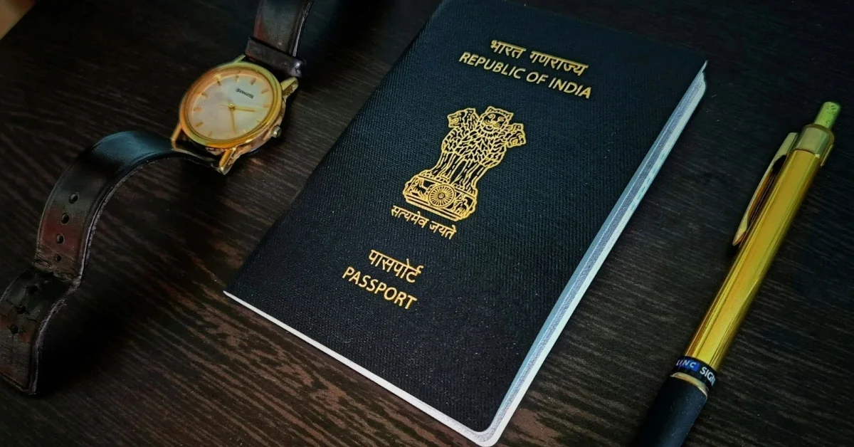 An Indian passport placed on a table next to a pen and a watch.