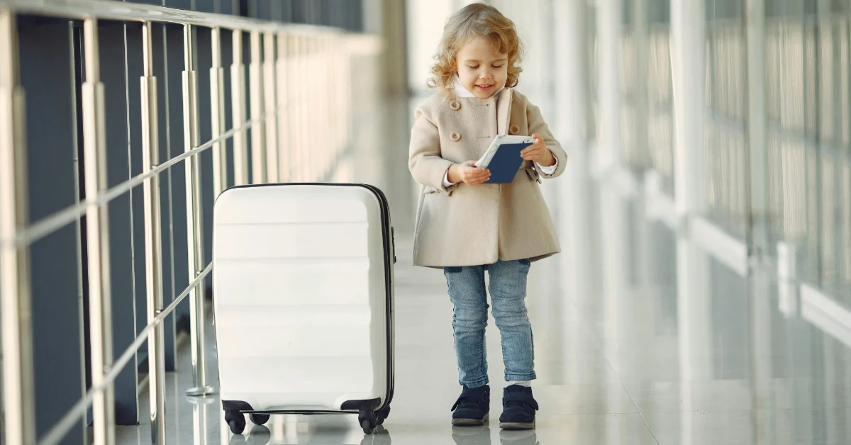 A smiling girl with two suitcases, all set to travel.