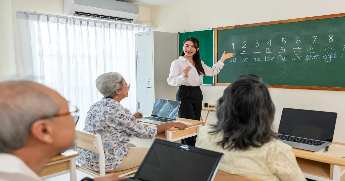 Asian female instructor teaching mature students in a classroom at school.