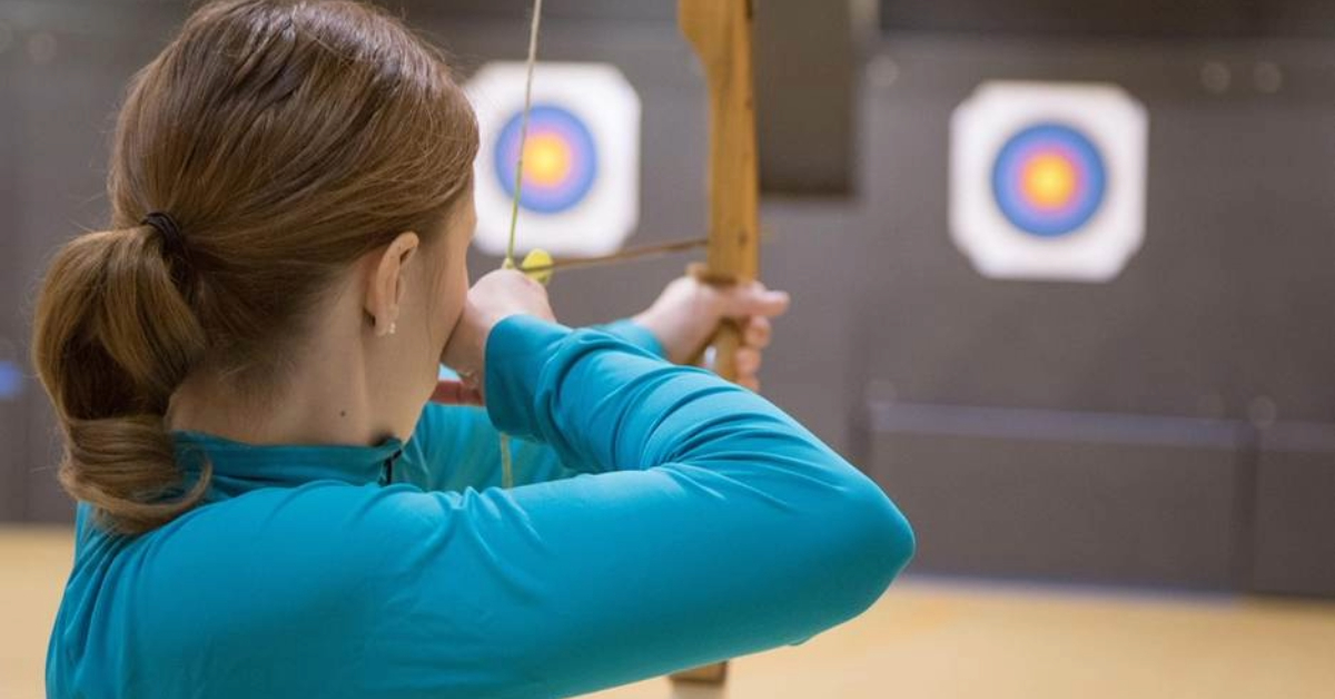 A woman practising archery in Dubai in an indoor setting