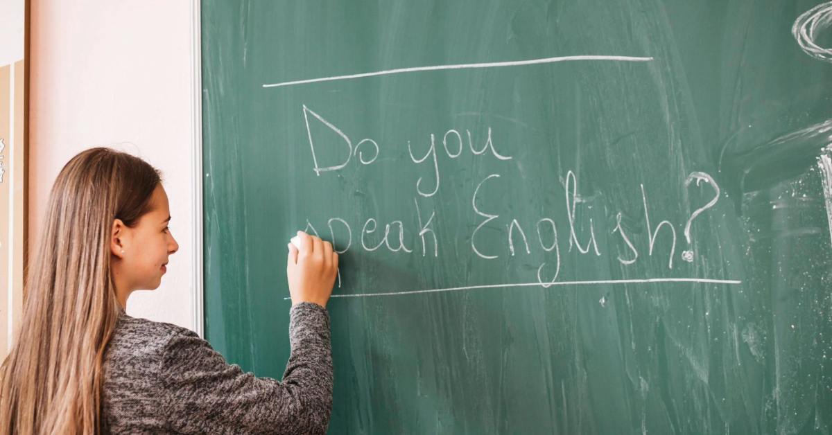 A teacher writing on blackboard with chalk