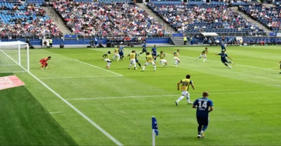 Side-angle shot of a football match taking place in the stadium.