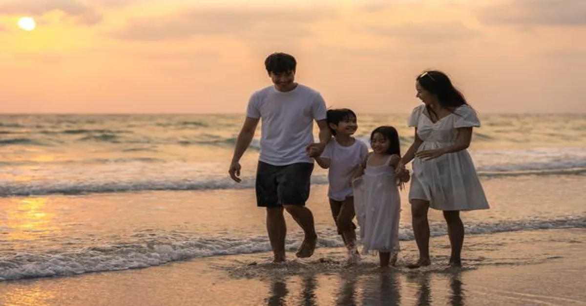 Family walking along a beach in Sharjah at sunset