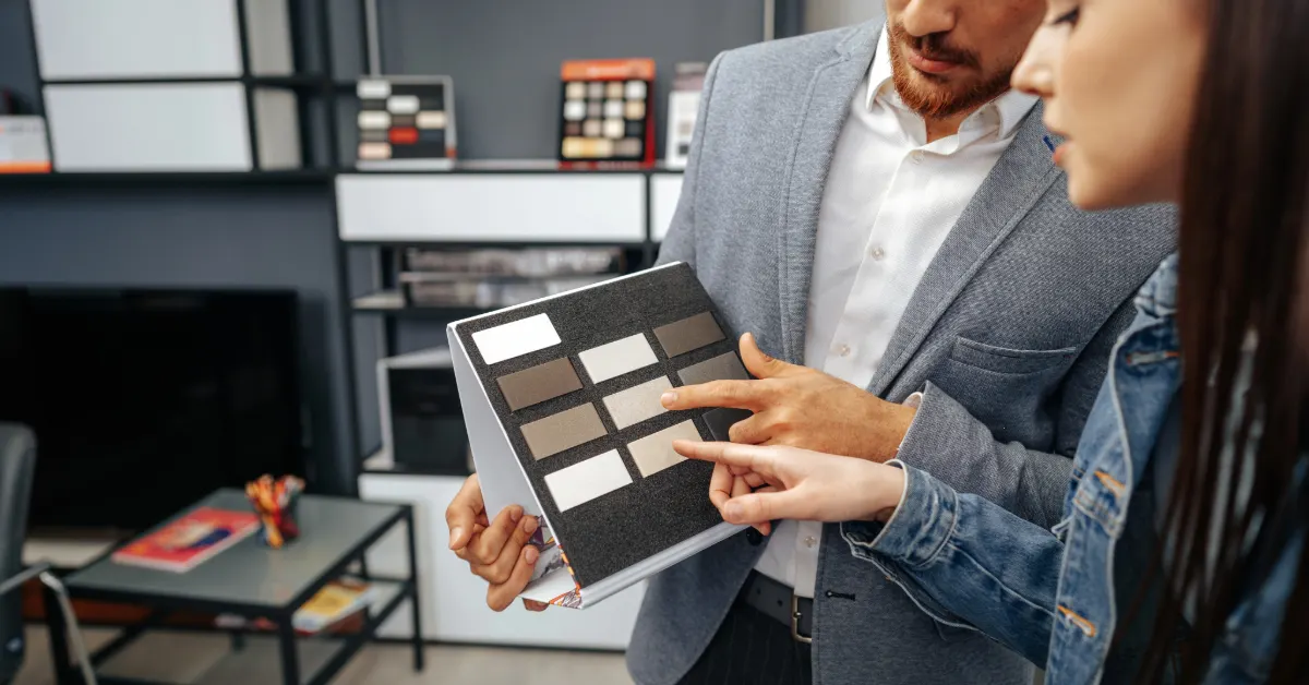 مصمم داخلي يعرض عينات ألوان رمادية لعميلة في متجر تصميم داخلي
