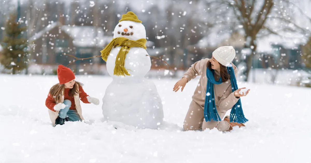 Mother and child girl playing with snowman