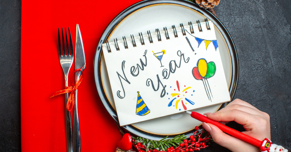 Above view of notebook with new year writing and drawings on a dinner plate