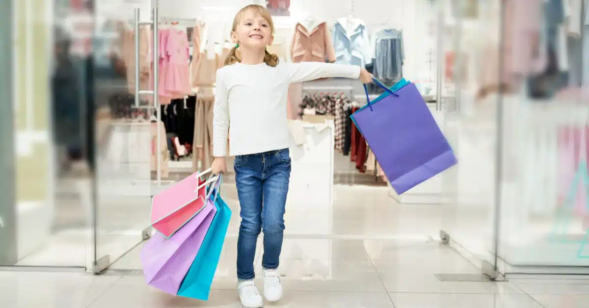 A happy child holding multiple shopping bags in a mall