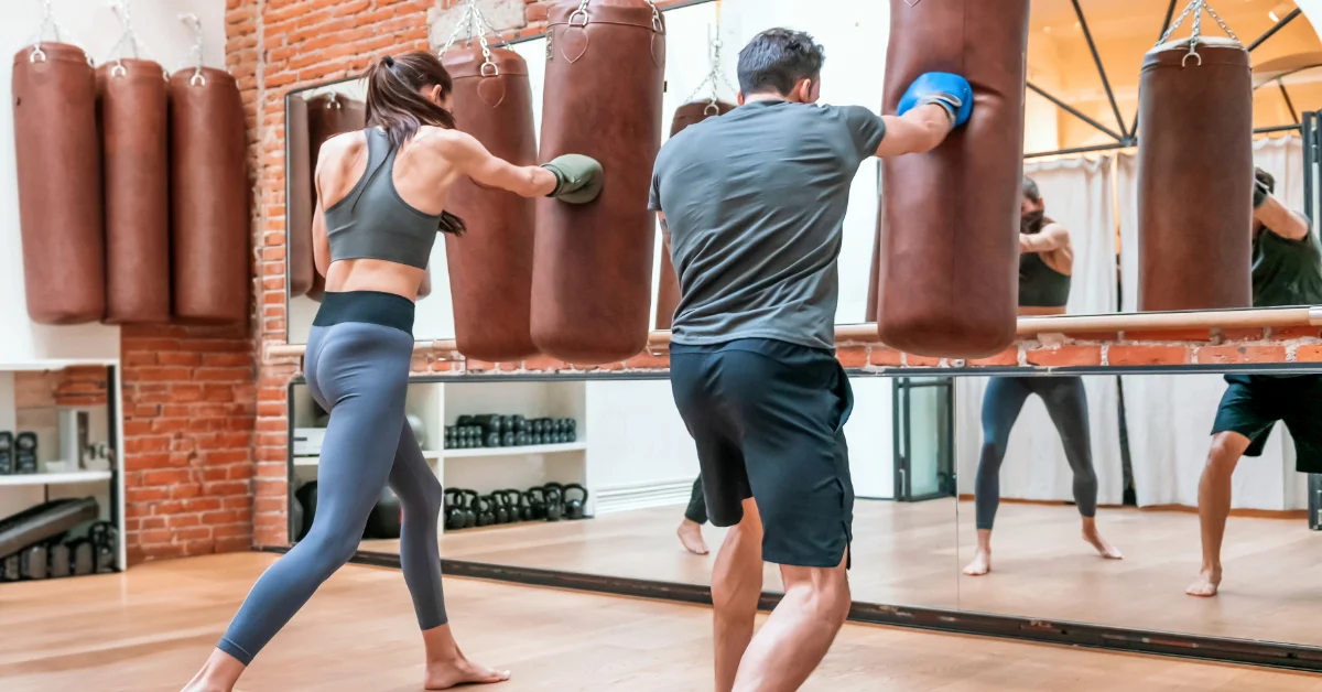 man and woman practicing on a punching bag