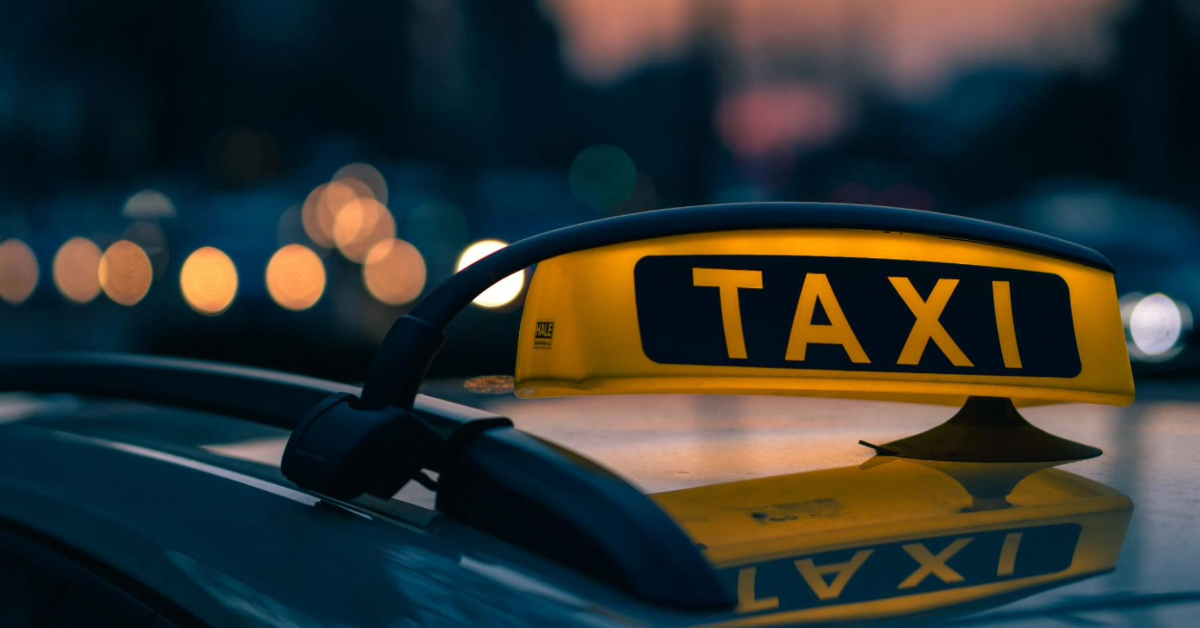 A close-up shot of a taxi sign set against the backdrop of sunset