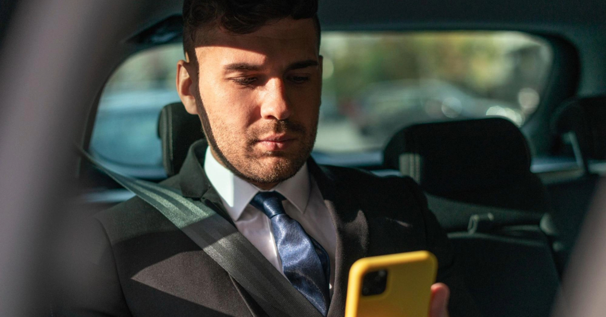 A passenger scrolling on their phone inside the taxi