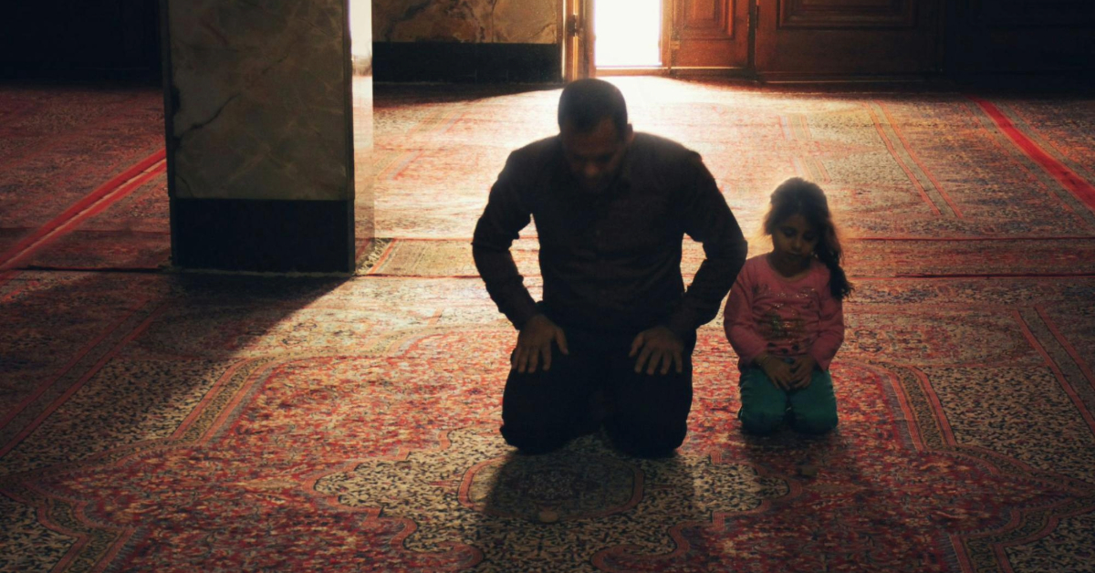 A silhouette of a father and daughter praying together