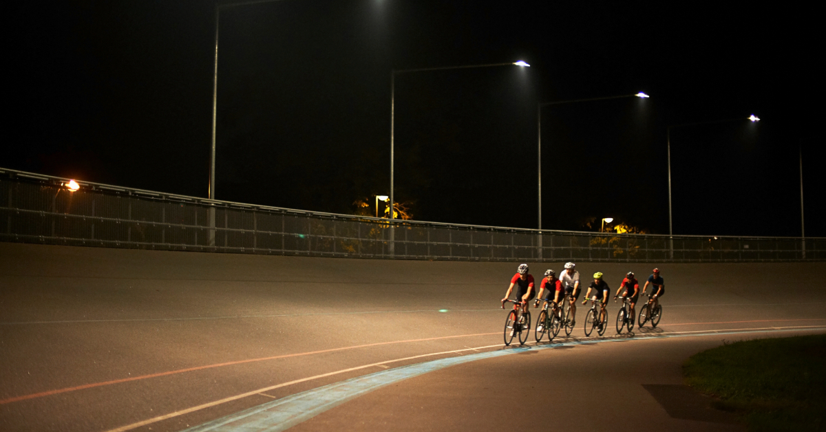 Cyclists riding together on a track at night