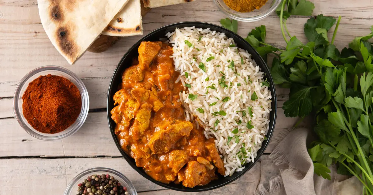 Indian butter chicken in black bowl on wooden table