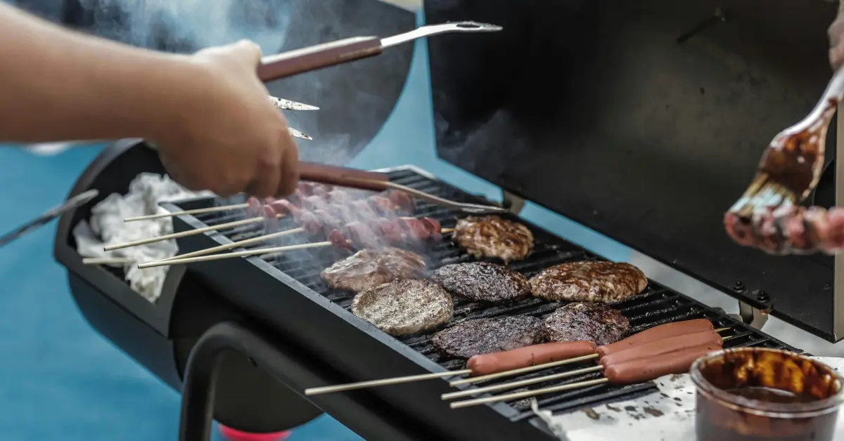Person grilling burgers and meat on a barbecue