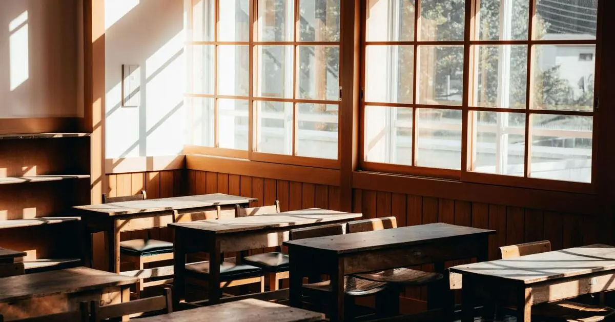 An empty classroom with wooden desks and benches