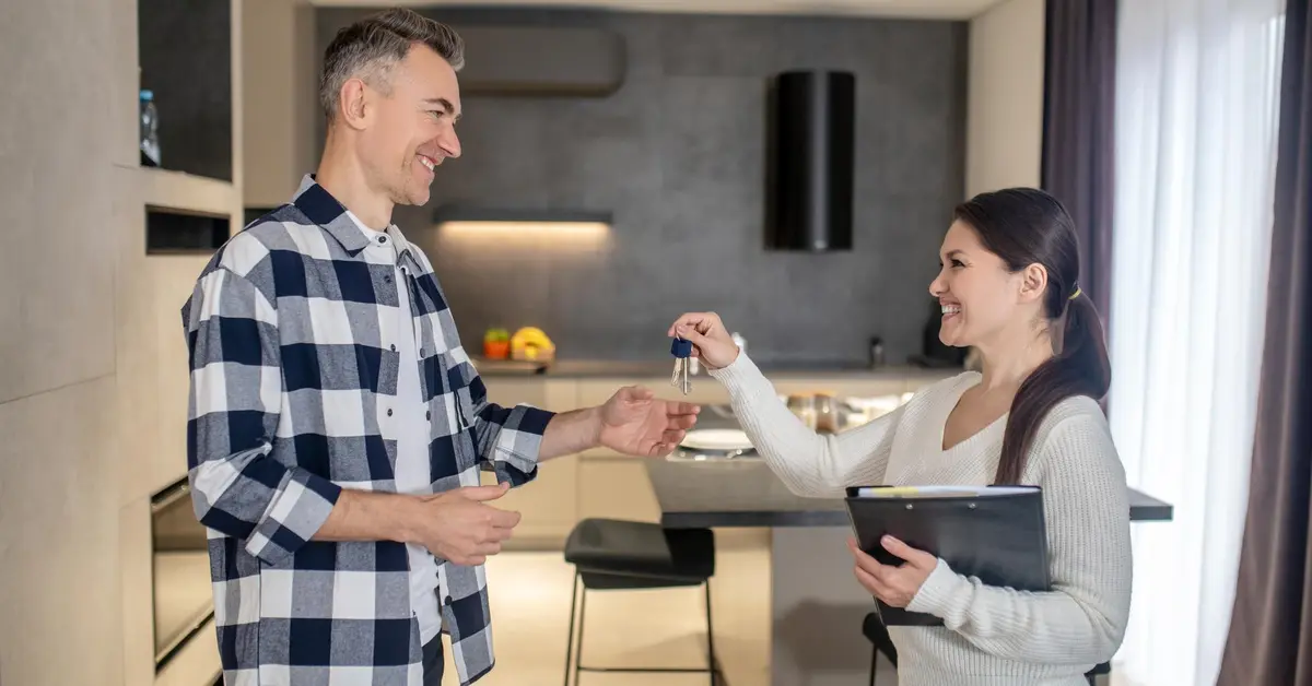 A man receiving his house keys after purchase from the women agent