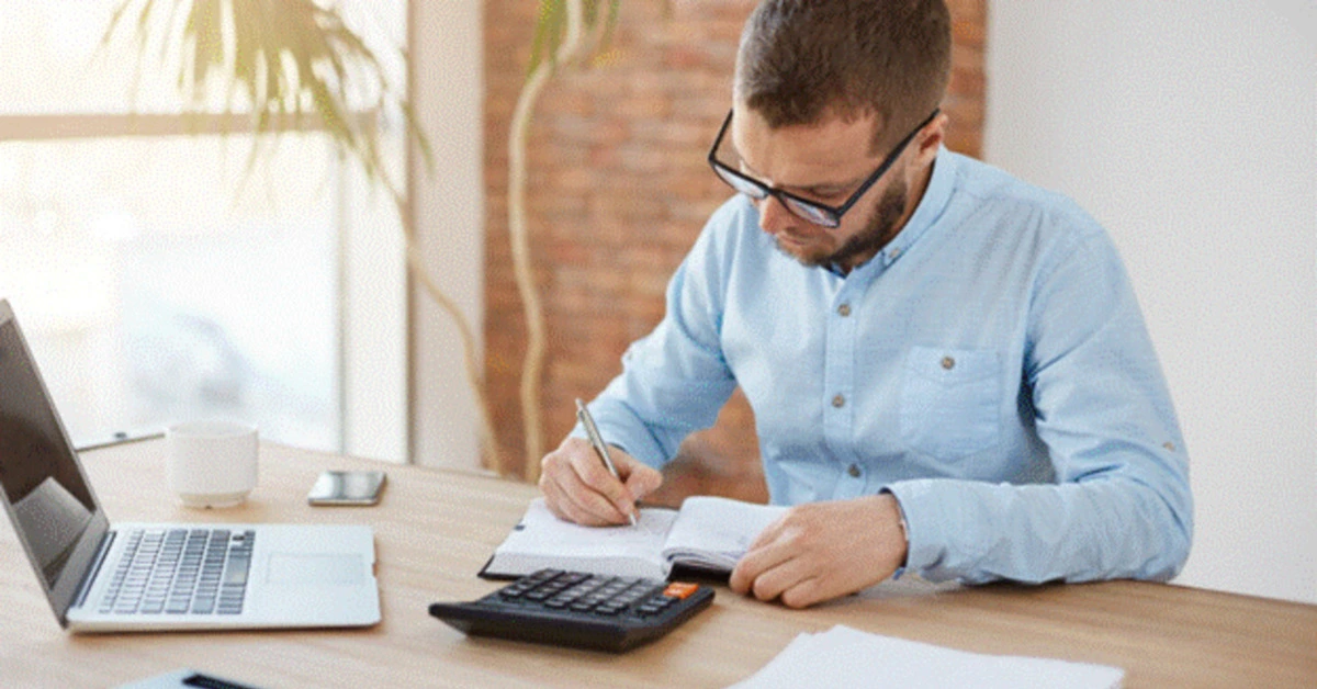 A man calculating his expenses as per the 50/30/20 rule