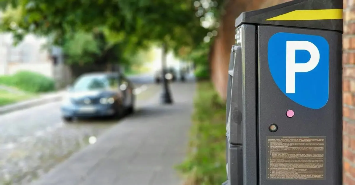 A car parked in the distance with the parking meter in focus