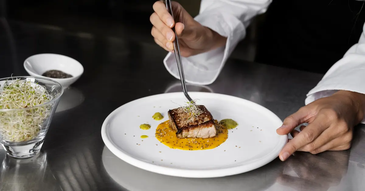 Female chef in the kitchen preparing plate of steak