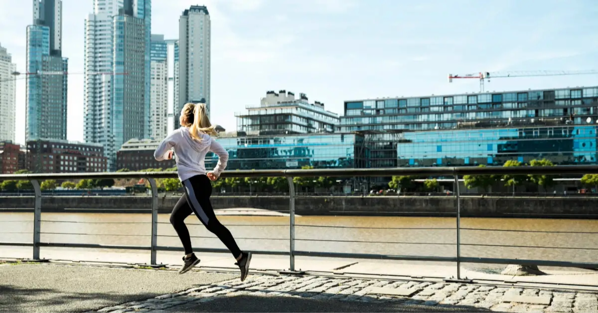 امرأة تركض على الممشى مع إطلالة على المباني الحديثة